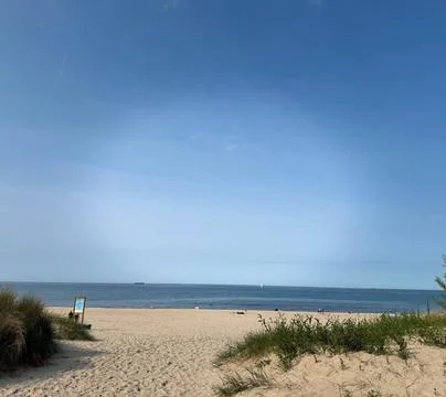 Serene Beach Scene with Sandy Path, Calm Sea, and Clear Blue Sky Stock Photos