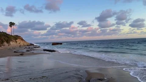 A serene beach scene at sunset with palm trees and calm waves in a peaceful Vídeos de archivo 333021740