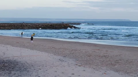 Serene Beach Scene with Waves and Surfers at Sunset Stock Footage 305263619