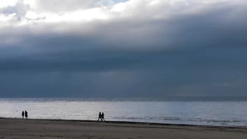 A serene beach setting with a dramatic sky and distant walkers enjoying the view Stock Footage 278925092