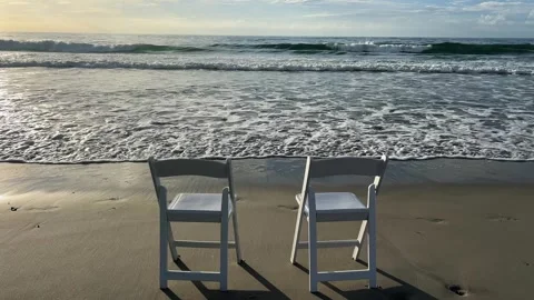 A serene beach with two folding chairs by gentle ocean waves 스톡 동영상 304841570