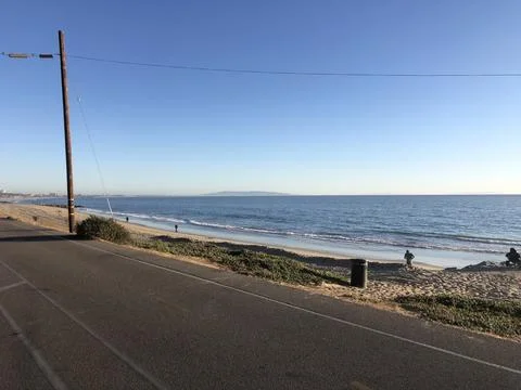 Serene Beach View With Gentle Waves Under a Clear Blue Sky at Sunset Stock Photos