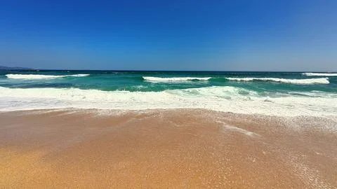 Serene Beach Waves Gently Rolling Under a Vast, Clear, and Beautiful Blue S.. Stock Photos