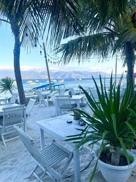 Serene beachside dining with view of clear waters and palm trees Stock Photos