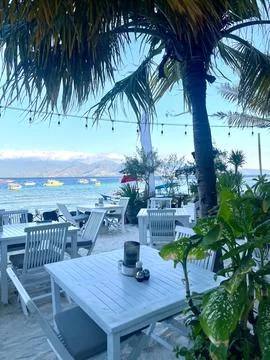 Serene beachside dining with view of clear waters and palm trees Stock Photos