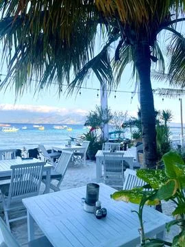 Serene beachside dining with view of clear waters and palm trees Stock Photos