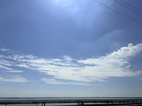 Serene Blue Sky with Wispy Clouds over Calm Water Foto stock