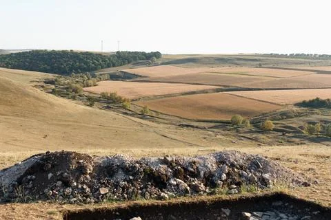 A serene calm landscape featuring rolling hills, scattered rocks, and patch.. Stock Photos