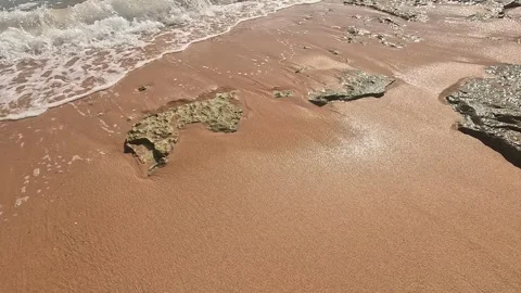 A Serene Coastal Scene Showcasing Soft Sand, Gentle Waves, and Irregular Rock Stock Footage 330100392
