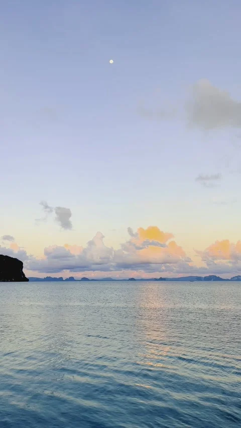 Serene Coastal View with Soft Clouds Reflected on Calm Water at Dusk Stock Footage 308772129