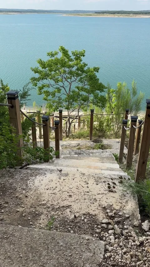 Serene descent down rustic lakeside stairs amid lush greenery and calm waters Stock Footage 315524735