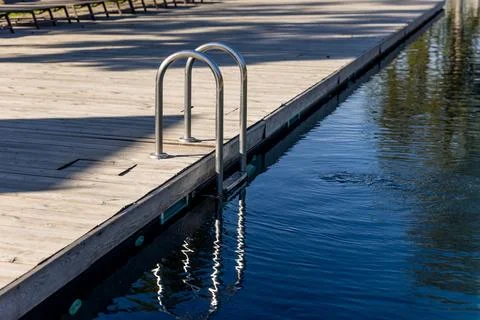 A Serene Dockside Setting Featuring a Sturdy Metal Ladder Leaning Over a Calm Stock Photos
