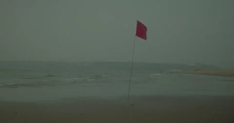 Serene Empty Beach with Red Flag Warning Under Cloudy Sky 스톡 동영상 327488530