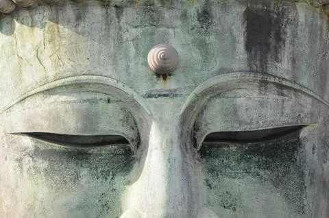 Serene expression on a weathered large Buddha statue face, close-up Stock Photos