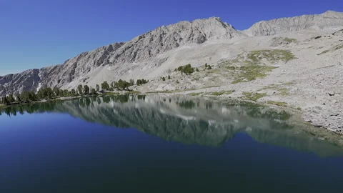 Serene FPV Flight: Mirror Lake Reflection with High-Alpine Peak Vistas Stock Footage 331896736