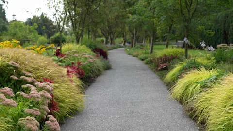 Serene Garden Path Surrounded by Lush Greenery and Colorful Flower Beds Stock Footage 315926498