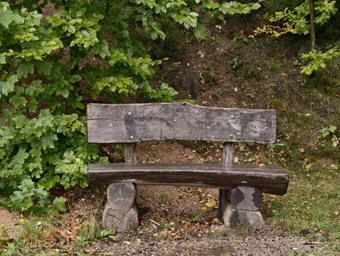 Serene handcrafted forest bench, charming rustic bench with stone supports and Stock Photos
