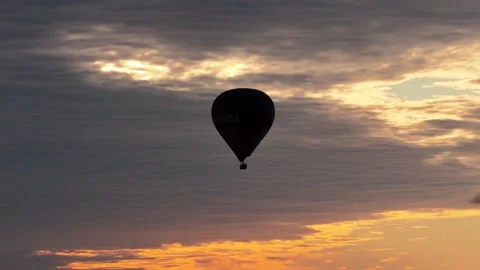 A serene horizontal view of a hot air balloon silhouette drifting over Vídeos de archivo 333451722