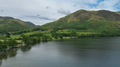 Serene lake mirrors distant, rolling hills under soft clouds Stock Footage 345524457