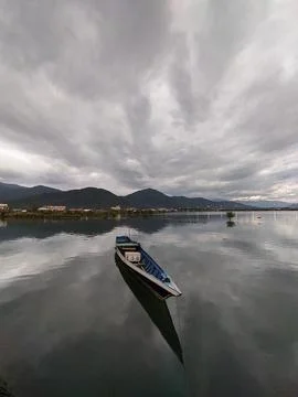 Serene lake reflecting dramatic clouds with solitary boat floating peacefully 스톡 사진