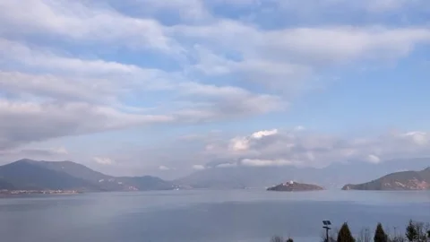 Serene Lake Reflection Under Dynamic Time-lapse Sky with Fast-Moving Clouds Stock Footage 328333968