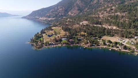 Serene Lakeside Community Aerial View with Mountains and Forest Stock Footage 258166345