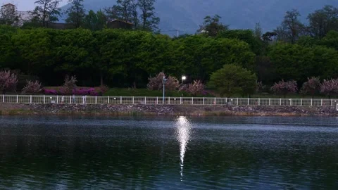 Serene lakeside landscape with tiny silhouettes of people walking by the canal Stock Footage 328140908