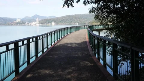 Serene Lakeside Path With Railing and Distant Hills View Stock Footage 268912631