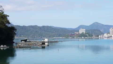Serene Lakeside View with Distant Mountains and Buildings Stock Footage 268907098