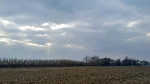 A serene landscape under a dramatic sky, showcasing a barren field bordered by Stock-Fotos