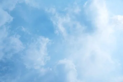 Serene light blue sky with soft, wispy white clouds, creating a peaceful and  Stock Photos