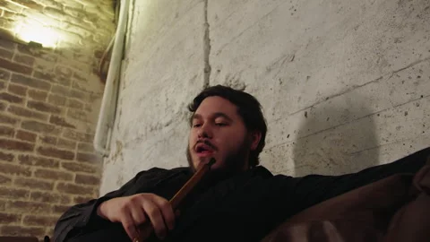 Serene man sits back and softly releases heavy cloud of smoke into air Video stock 331880894