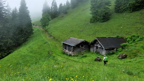 The serene mountain landscape has rustic cabins in misty surroundings, ideal for Stock Footage 315967985