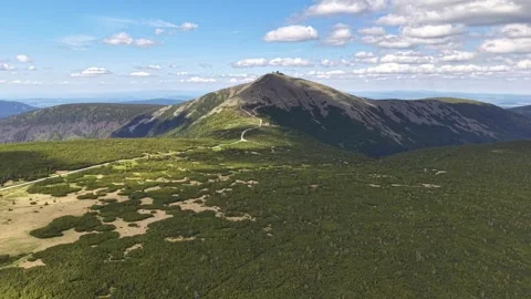 Serene mountain landscape with open field and partly cloudy sky under a Stock Footage 342355392