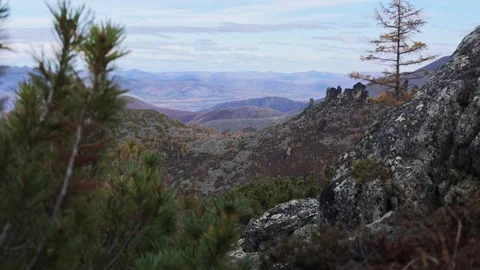 Serene mountain ridges under partly cloudy sky framed by pine branches Stock Footage 346278932