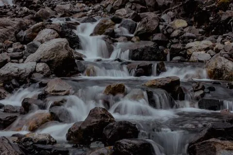 Serene mountain stream flows over smooth rocks, creating a tranquil scene in Stock Photos