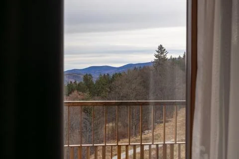 A serene mountain view framed through an open hotel balcony window, showcasing Stock Photos