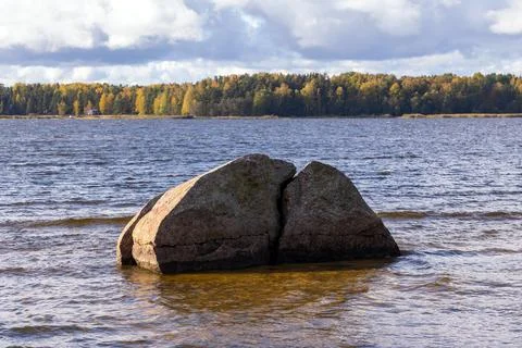 A serene natural scene of a large split rock in a tranquil lake Stock Photos