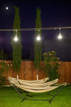 A serene nighttime backyard featuring two well-maintained hammocks on a gra.. Stock Photos