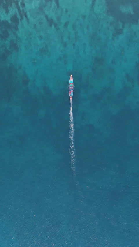 Serene ocean boat navigating through clear sea waters aerial top view vertical Stock Footage 312501507