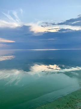 Serene ocean horizon with dramatic clouds reflecting on calm, blue water su.. Stockfoto's