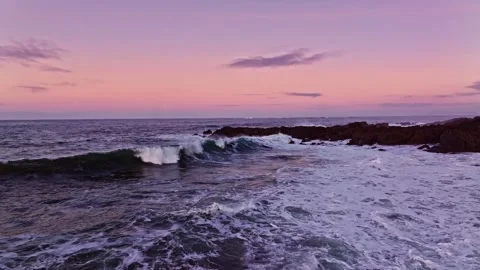 The Serene Ocean Waves Are Gently Lapping at Sunset Beneath a Beautiful Pink Sky Stock Footage 303703769