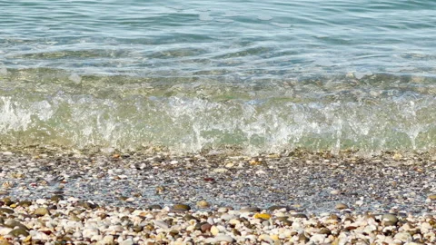 Serene Ocean Waves Gently Crash and Bubble Against a Smooth Pebble Beach Stock Footage 334122153