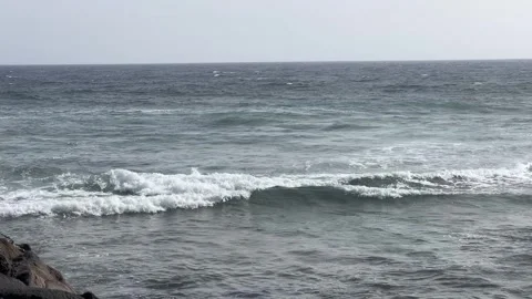 Serene Ocean Waves Gently Crashing upon Rugged Rocky Shoreline with Scenic Stock Footage 317075914