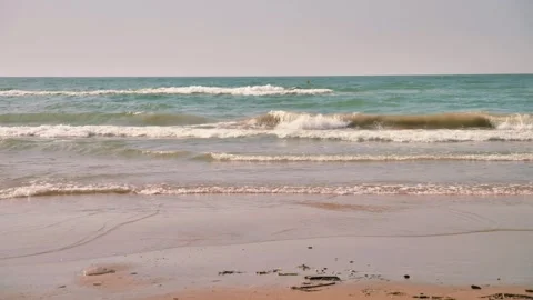 Serene ocean waves gently roll onto a sandy beach under a soft pastel sky. Stock Footage 313844901