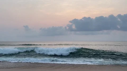 Serene ocean waves rolling onto a sandy beach at sunset Vidéo 334084193