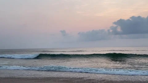 Serene ocean waves rolling onto the sandy shore during a soft, pastelcolored Stockbeeldmateriaal 334163992