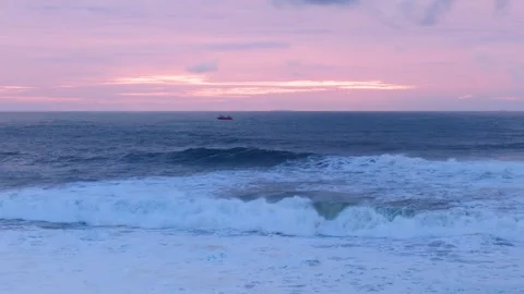 Serene Ocean Waves Under a Vibrant Pink Sunset. Horizon is illuminated by the Stock Footage 296696553