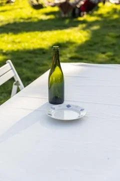 A Serene Outdoor Dining Setup Featuring a Green Bottle on a White Tablecloth Stock-Fotos