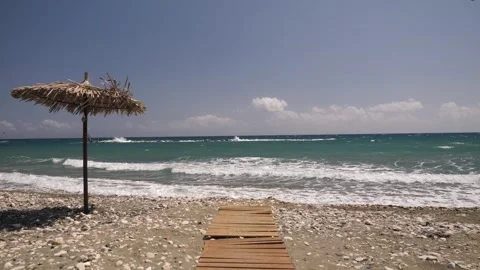 A Serene, Picturesque Beach View Featuring an Umbrella and a Charming Wooden Video stock 302173360